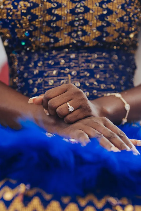 Main d'une mariée portant sa bague, en tenue traditionnelle bleu et or